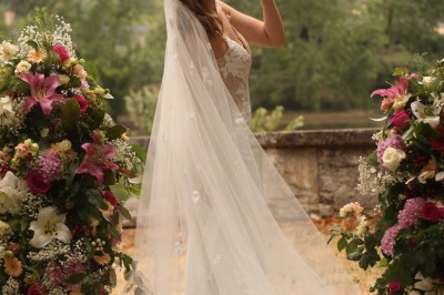 Miniature cérémonie laïque Un couple en tenue de mariage marche dans une salle en briques, avec un bouquet de fleurs au premier plan.