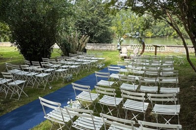 Miniature cérémonie laÏque Un couple en tenue de mariage marche dans une salle en briques, avec un bouquet de fleurs au premier plan.
