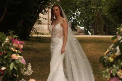 Miniature dans le parc Un couple en tenue de mariage marche dans une salle en briques, avec un bouquet de fleurs au premier plan.