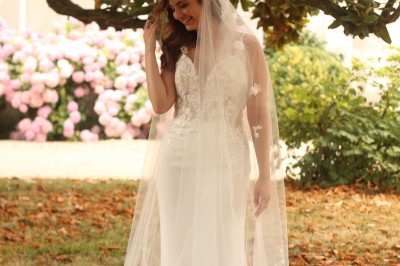 Miniature dans le parc Un couple en tenue de mariage marche dans une salle en briques, avec un bouquet de fleurs au premier plan.