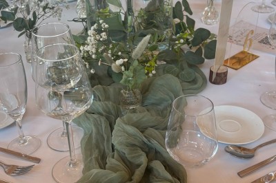 Miniature décoration de table Un couple en tenue de mariage marche dans une salle en briques, avec un bouquet de fleurs au premier plan.