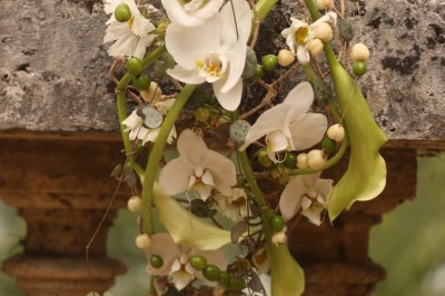 Miniature décoration Un couple en tenue de mariage marche dans une salle en briques, avec un bouquet de fleurs au premier plan.