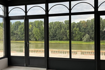 Miniature la Garonne vu de la salle Un couple en tenue de mariage marche dans une salle en briques, avec un bouquet de fleurs au premier plan.