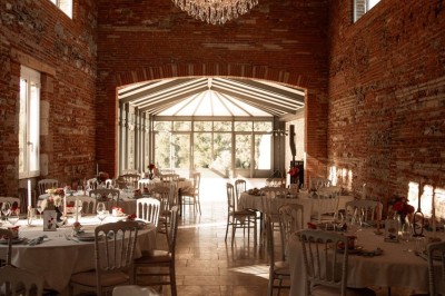 Miniature la salle de réception Un couple en tenue de mariage marche dans une salle en briques, avec un bouquet de fleurs au premier plan.