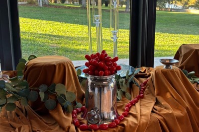 Miniature la salle Un couple en tenue de mariage marche dans une salle en briques, avec un bouquet de fleurs au premier plan.