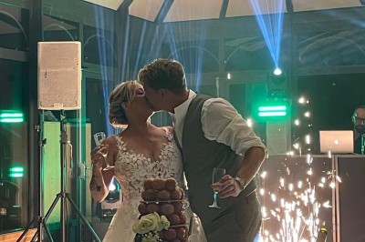 Miniature superbe mariage Un couple en tenue de mariage marche dans une salle en briques, avec un bouquet de fleurs au premier plan.