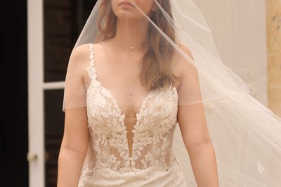 Miniature sur perron du château Un couple en tenue de mariage marche dans une salle en briques, avec un bouquet de fleurs au premier plan.