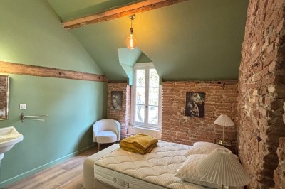 Miniature une chambre dans le gîte maison de gardien Un couple en tenue de mariage marche dans une salle en briques, avec un bouquet de fleurs au premier plan.