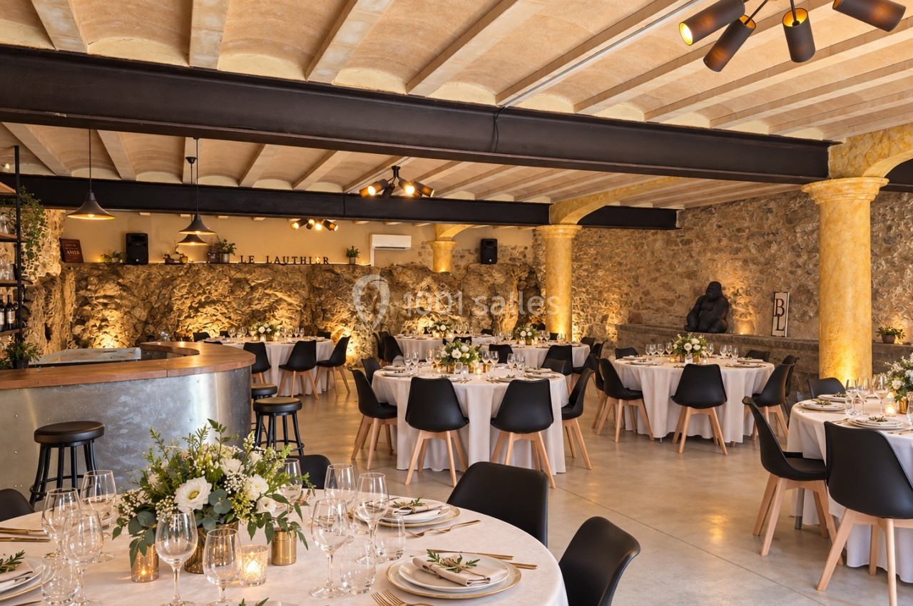 Salle de réception élégante avec tables rondes décorées de fleurs, chaises noires et éclairage chaleureux.