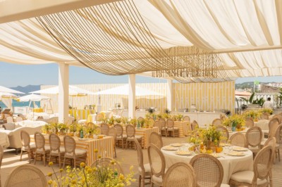 Miniature J&b Event #2 Chaises en rotin entourées de pampas et de décorations jaunes, sous un parasol blanc dans un cadre lumineux.