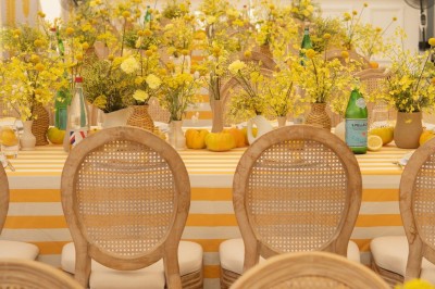 Miniature J&b Event #13 Chaises en rotin entourées de pampas et de décorations jaunes, sous un parasol blanc dans un cadre lumineux.