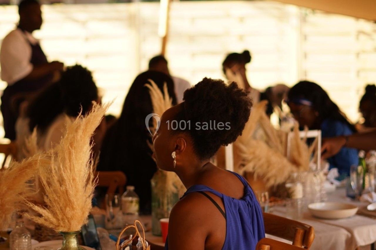 Des personnes assises à une table décorée de pampas, discutant dans une ambiance conviviale et lumineuse.