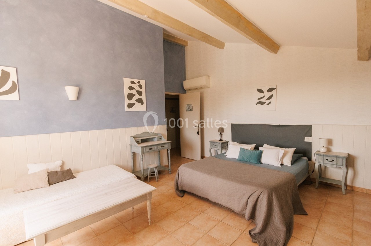 Chambre lumineuse avec un lit double, un lit simple, des meubles en bois clair et des murs décorés de cadres.
