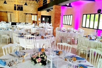 Table en bois avec un chapeau, un flacon de parfum, des sandales, un bouquet de fleurs et une bague devant un mur de briques.