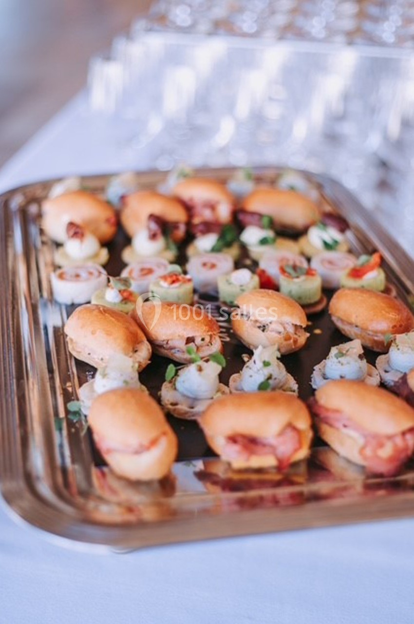 Plateau de petits fours variés, comprenant des mini-sandwichs et des bouchées garnies, disposé sur une table blanche.