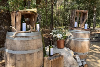 Miniature Location salle Chanteau (Loiret) - Domaine de la Foret #36 Deux tonneaux en bois décorés avec des bouteilles de vin, des fleurs et des caisses, dans un cadre extérieur boisé.