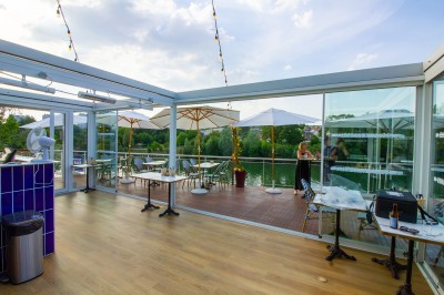 Miniature Location salle Lagny-sur-Marne (Seine-et-Marne) - Aux Deux Barrés #1 Terrasse extérieure avec bar en carrelage violet, tables, parasols et guirlandes lumineuses sous un ciel dégagé.