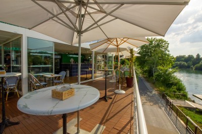 Miniature Location salle Lagny-sur-Marne (Seine-et-Marne) - Aux Deux Barrés #3 Terrasse extérieure avec bar en carrelage violet, tables, parasols et guirlandes lumineuses sous un ciel dégagé.