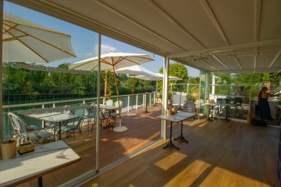 Miniature Location salle Lagny-sur-Marne (Seine-et-Marne) - Aux Deux Barrés #6 Terrasse extérieure avec bar en carrelage violet, tables, parasols et guirlandes lumineuses sous un ciel dégagé.