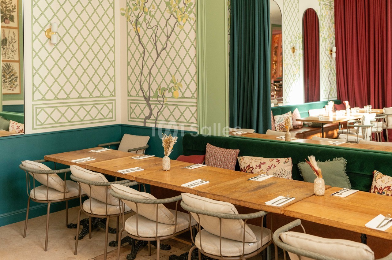 Salle à banquette verte avec table en bois, chaises beige, panneaux géométriques verts et rouges - Jardin Folia.