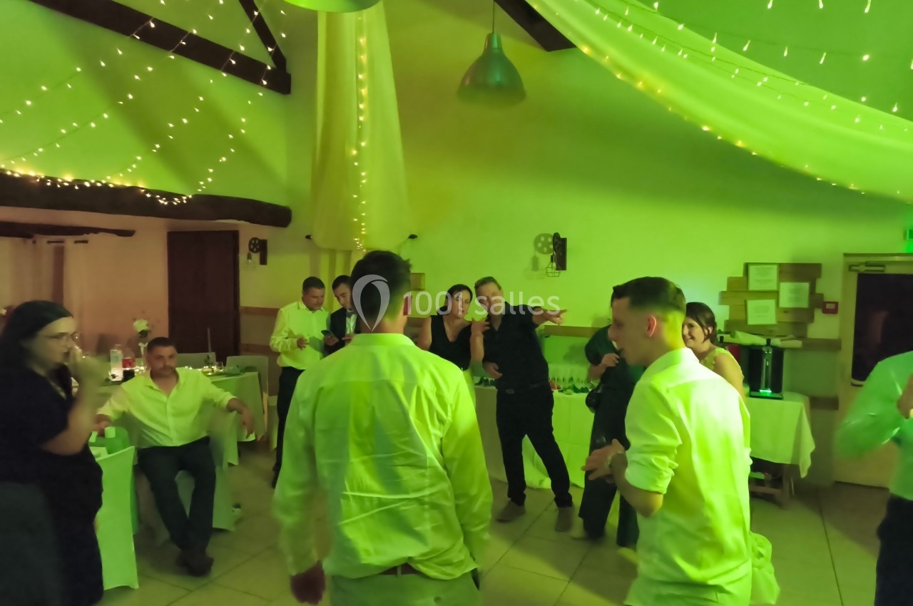 Des personnes dansent et discutent dans une salle décorée de guirlandes lumineuses lors d'un événement festif.