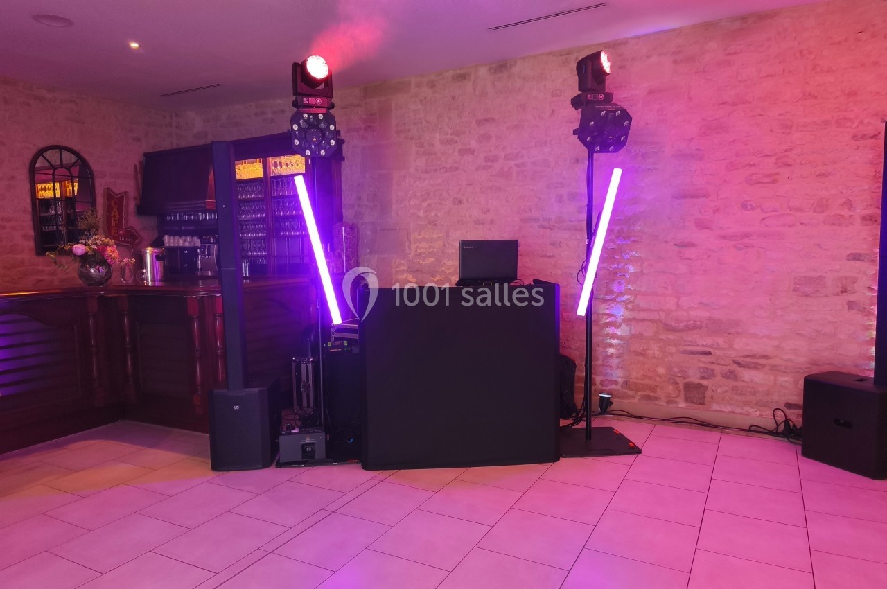 Installation de matériel de sonorisation et éclairage avec jeux de lumières dans une salle aux murs en pierre.