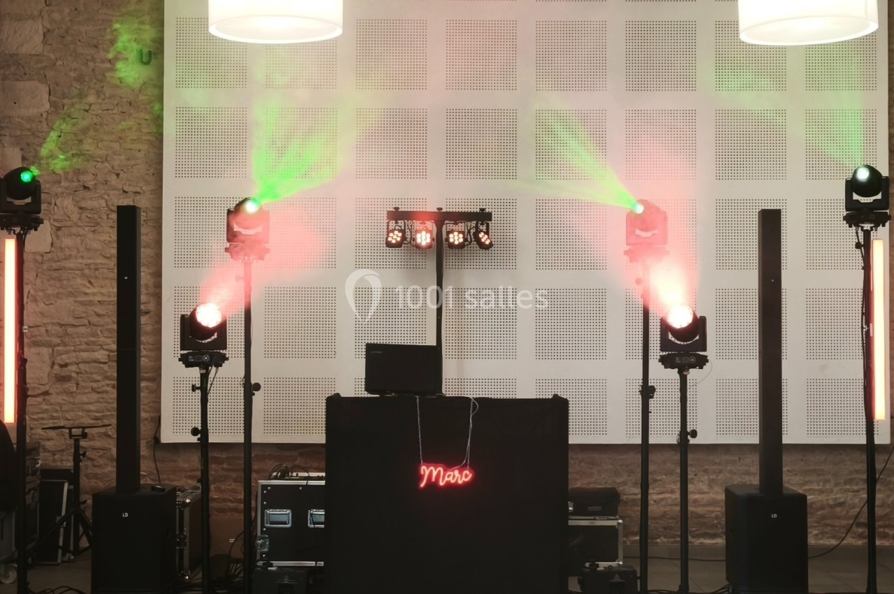 Installation de matériel de sonorisation et éclairage avec projecteurs colorés et panneau lumineux rouge.
