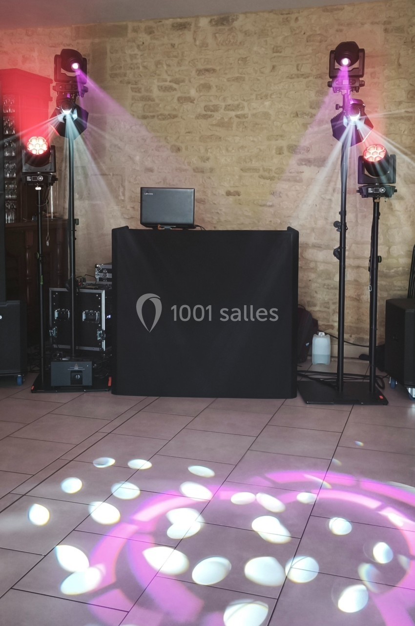 Installation de matériel de sonorisation et d'éclairage avec projecteurs colorés dans une salle en pierre.
