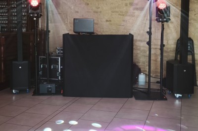 Miniature DJ Caen (Calvados) - Marc Leodo #2 Un homme portant un casque audio se tient devant un mur en pierre éclairé par une lumière rose.