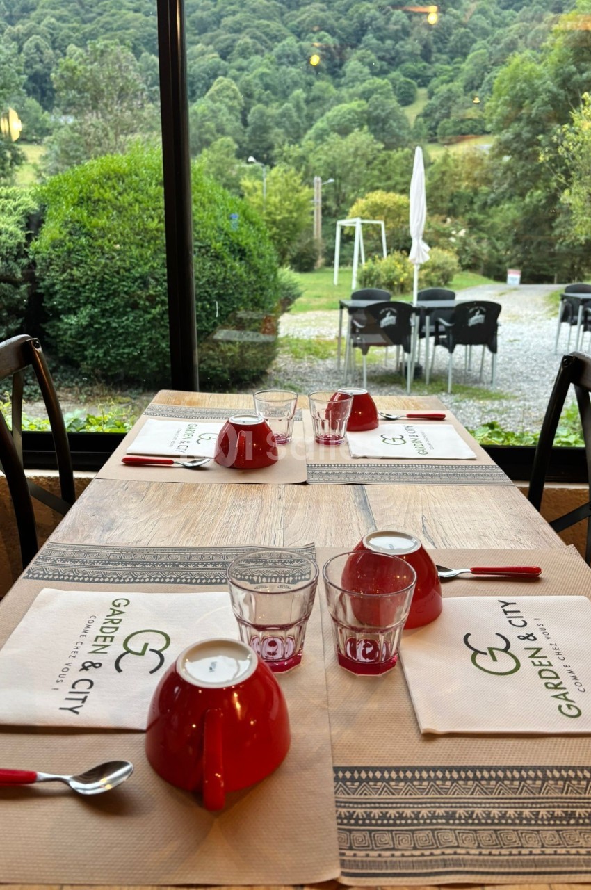 Table en bois dressée de assiettes creuses rouges, verres à pied... Let me write it properly in French, one sentence, under 125 characters, no "Photo de", no transcription of the napkin text "Garden & City" (it's text in the image, so I must not