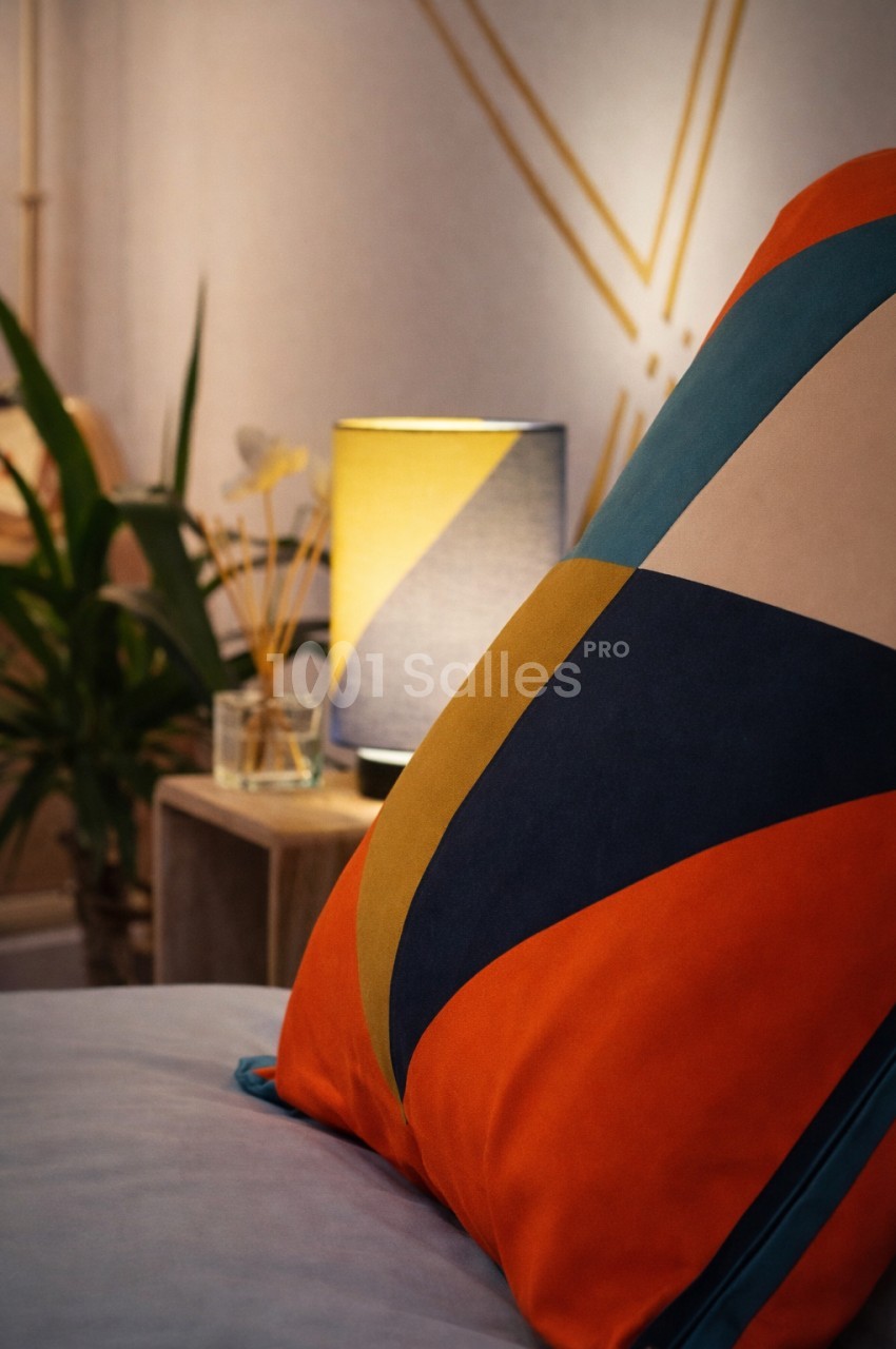 Coussin géométrique aux bandes orange, bleu et or en gros plan - ambiance intérieure contemporaine.