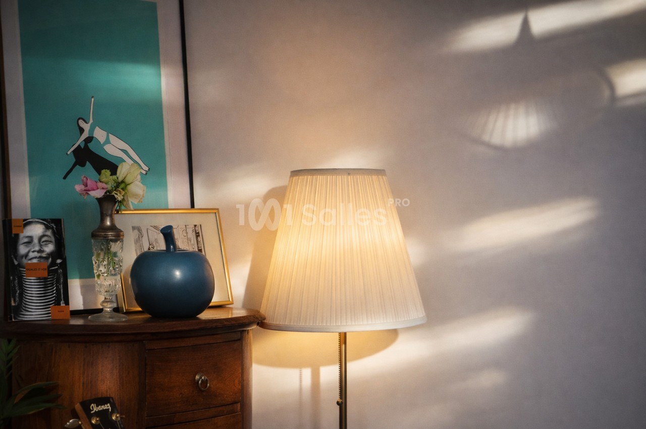 Lampadaire à abat-jour plissé beige dans un intérieur avec mur turquoise et meubles vintage.