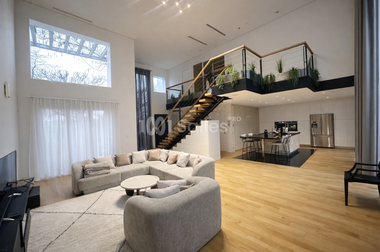 Intérieur contemporain avec salon modulaire gris clair, escalier bois et métal desservant mezzanine végétalisée, cuisine îlot, parquet clair et large baie vitrée.