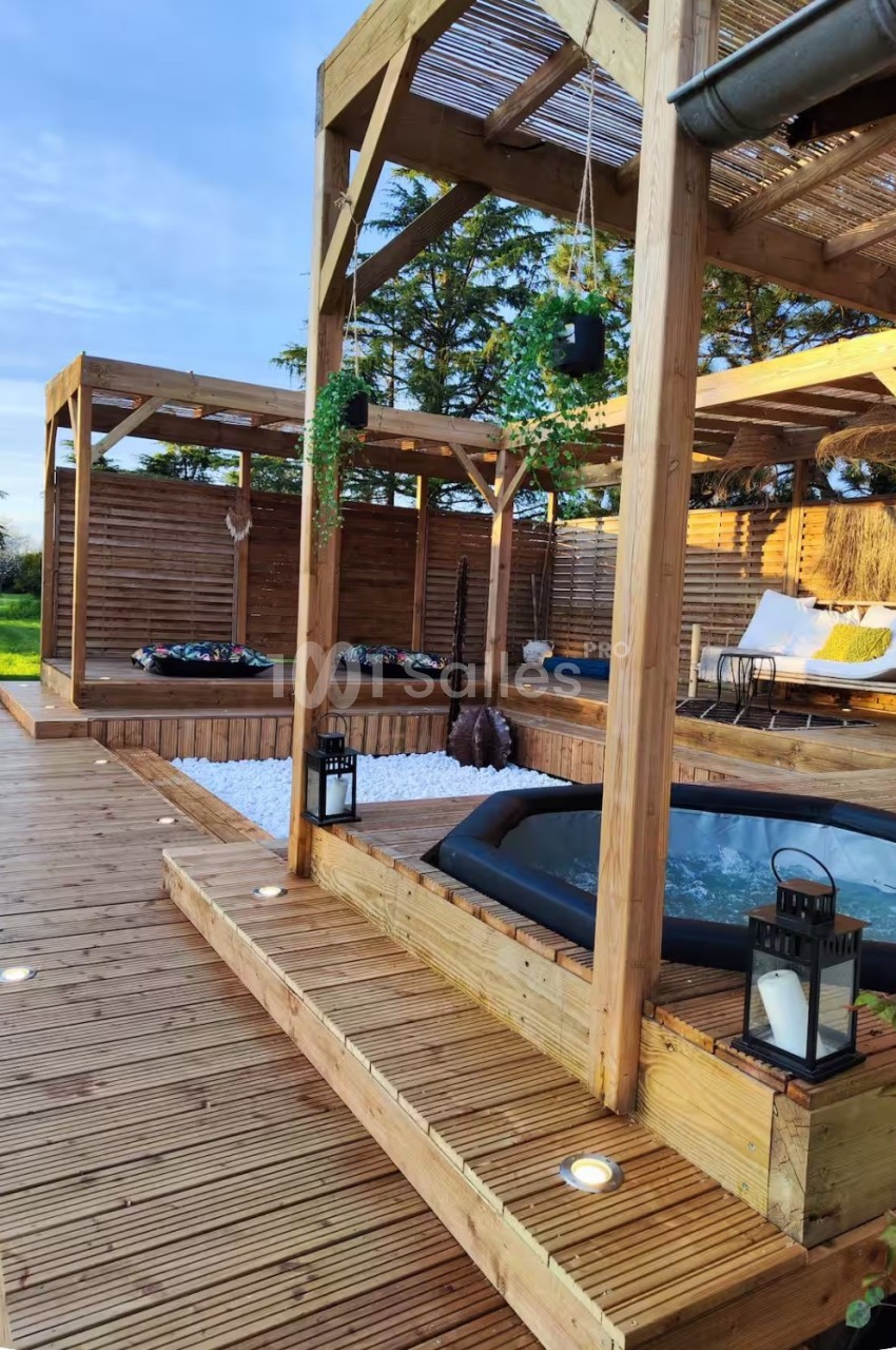 Espace lounge extérieur avec terrasse bois, pergolas en bois, bassin de détente et zones d'assise aménagées.