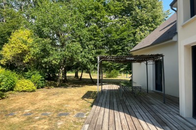 Intérieur d'une tente événementielle avec sol rose, tables blanches et vue sur un espace extérieur verdoyant.
