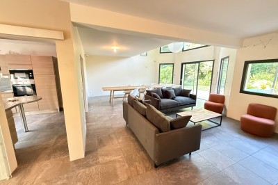 Intérieur d'une tente événementielle avec sol rose, tables blanches et vue sur un espace extérieur verdoyant.
