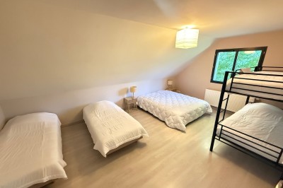 Salle de bain mansardée avec douche d'angle, lavabo intégré, carrelage blanc et murs partiellement peints en violet.