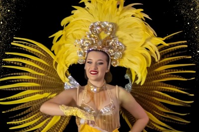 Miniature Cabaret Pierre de Lune #2 Danseuse en costume rose à plumes sur fond sombre, avec icônes de réseaux sociaux et texte ’Retrouvez nous sur nos réseaux…