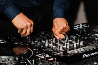 Mains ajustant les commandes d'une table de mixage audio dans un environnement sombre.