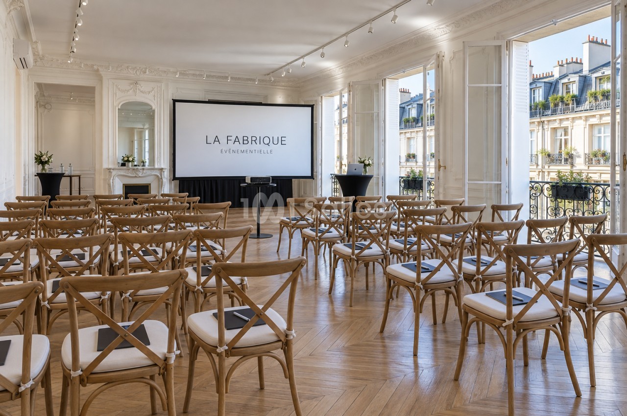 Salle de réception parisienne aux moulures blanches et parquet en chevron, dressée en conférence avec chaises en bois à dossier croisé face à un grand écran, grandes portes-fenêtres ouvertes sur un balcon. Let me check length: roughly 200 characters, too