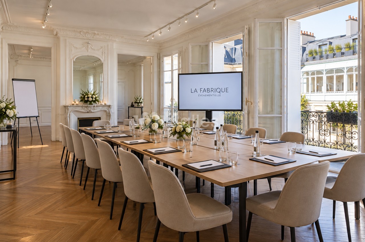 Salle de réunion aux moulures blanches et parquet en point de Hongrie, avec une grande table dressée pour une vingtaine de personnes, face à un écran. Let me check length: roughly 150 characters, too long. Need ≤125. Salle de réunion haussmannienne aux