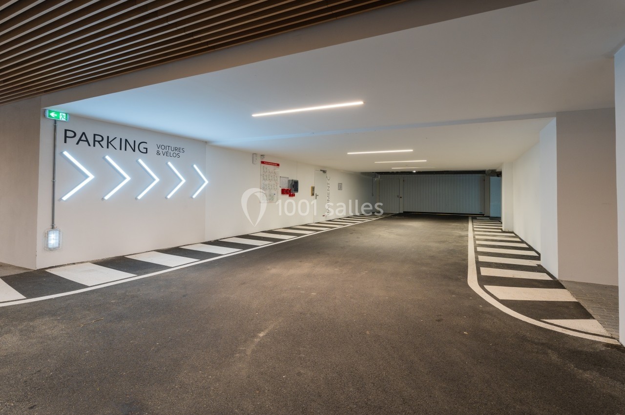 Entrée d'un parking intérieur avec signalisation lumineuse indiquant les directions pour voitures et vélos.