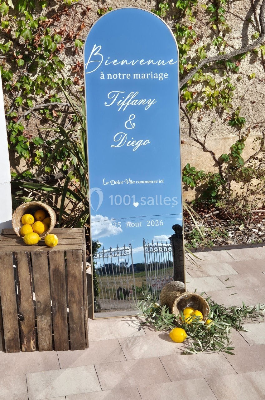 Panneau miroir décoratif annonçant un mariage, entouré de citrons, d'olives et d'une caisse en bois, devant un mur…
