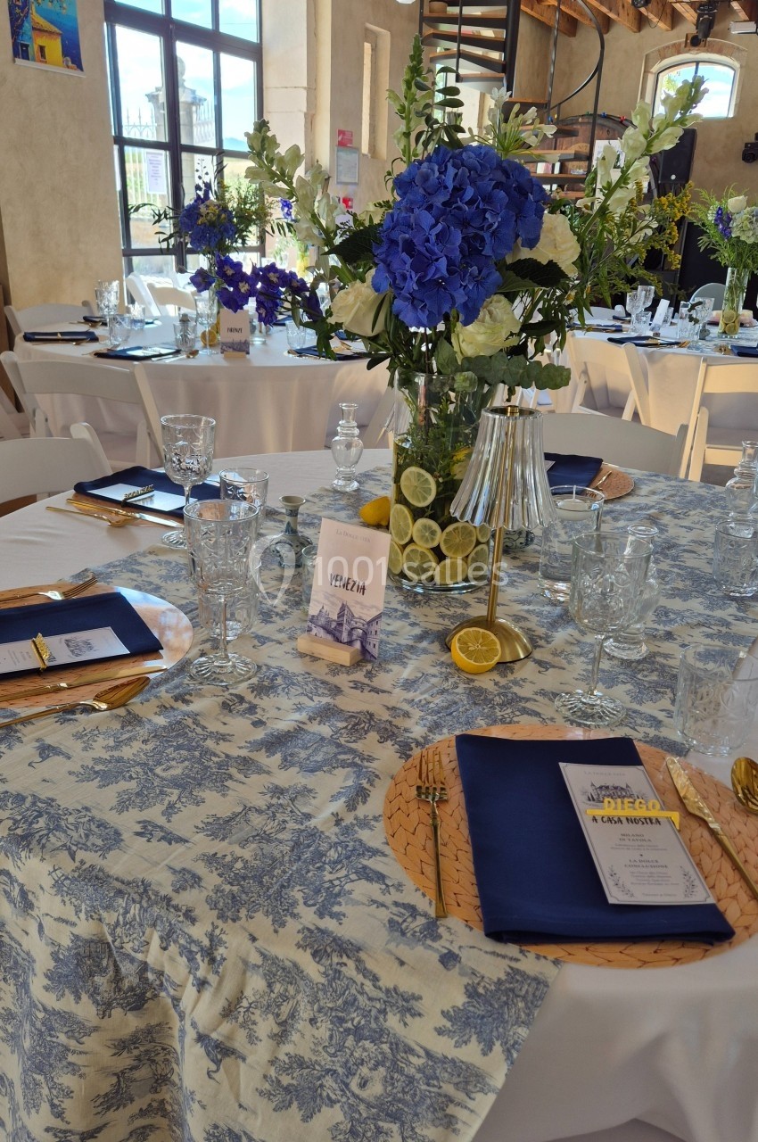 Table de réception décorée avec une nappe à motifs, un centre de table floral bleu et blanc, et des accessoires élégants.