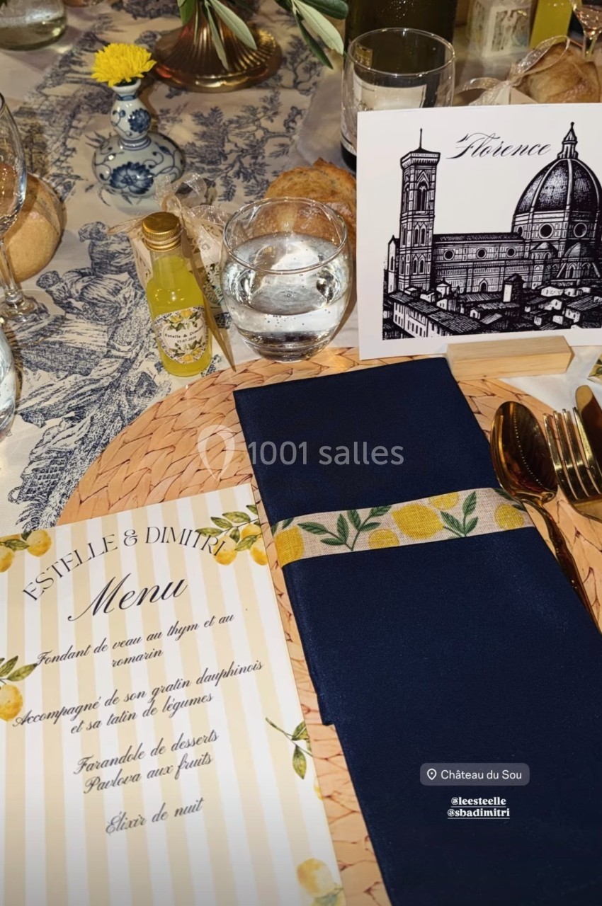 Table dressée avec un menu, une serviette bleue, une carte illustrée de Florence et des éléments décoratifs.