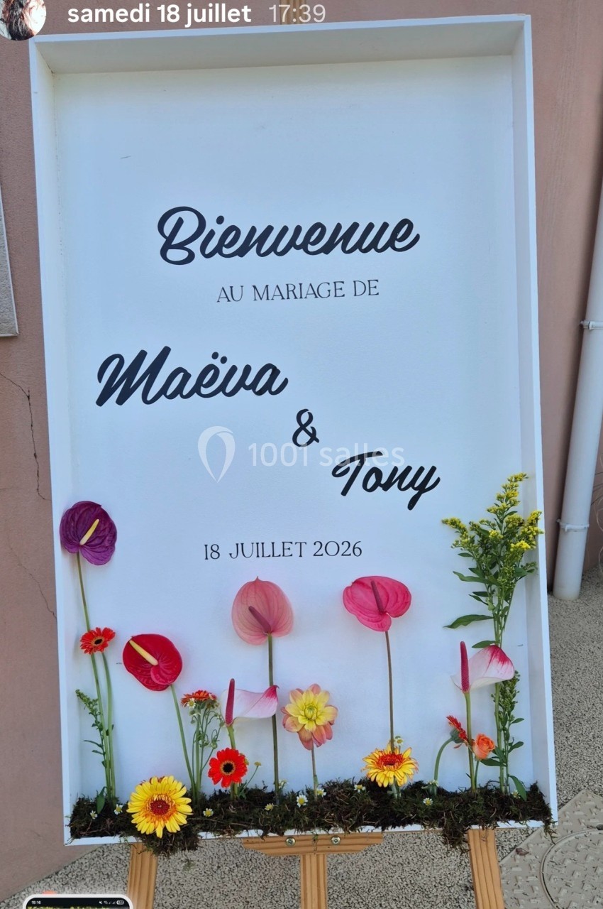 Panneau de bienvenue pour un mariage, décoré de fleurs colorées sur un fond blanc, avec des prénoms et une date.