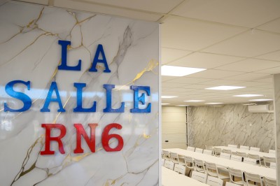 Salle de bain moderne avec lavabo, miroir rond, toilettes et urinoir, murs en marbre et sol carrelé.