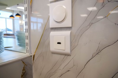 Salle de bain moderne avec lavabo, miroir rond, toilettes et urinoir, murs en marbre et sol carrelé.