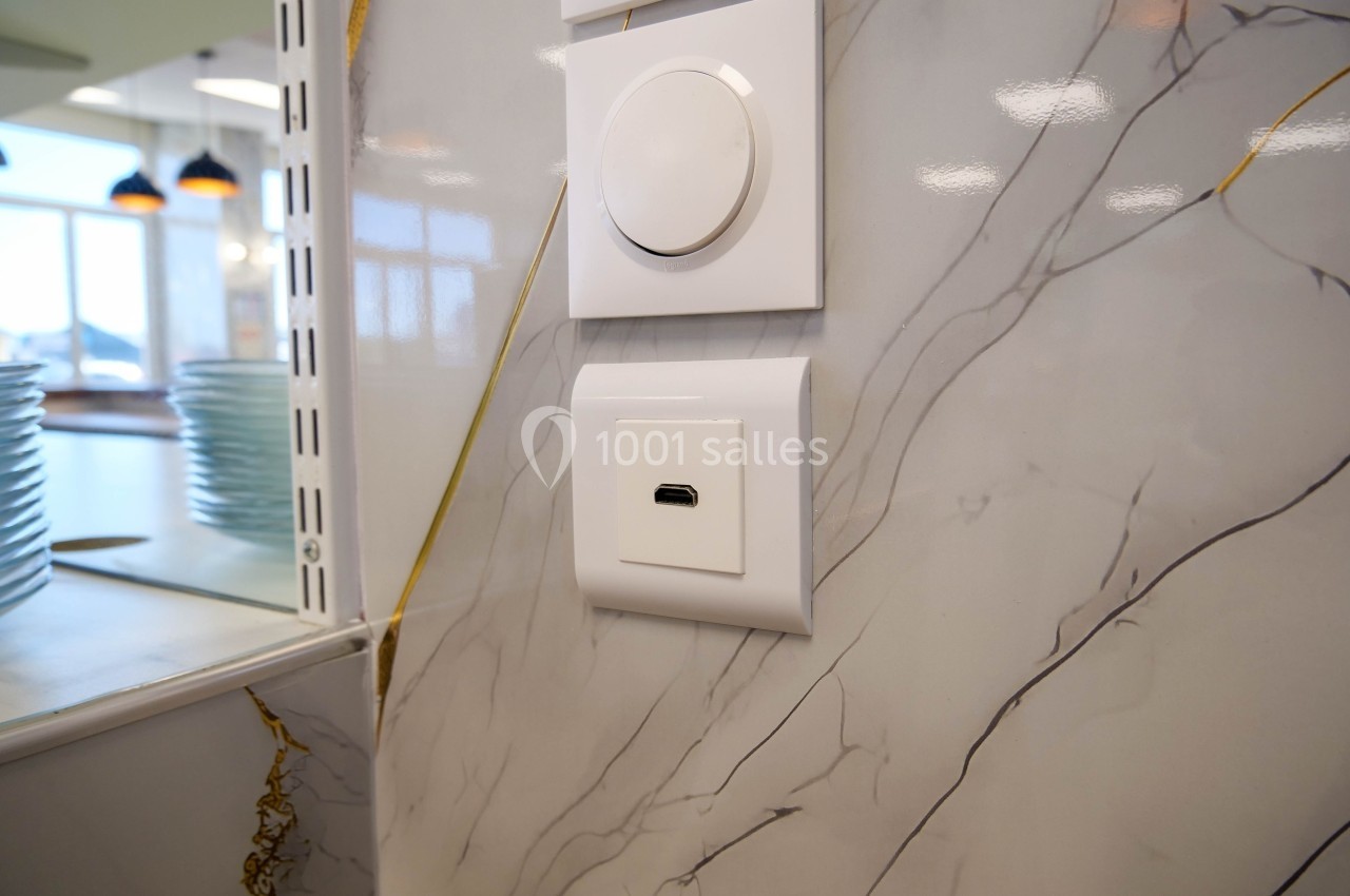 Prise murale USB-C encastrée sur un mur en marbre clair, près d'une étagère avec des assiettes.