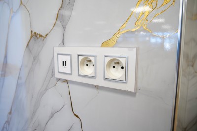 Salle de bain moderne avec lavabo, miroir rond, toilettes et urinoir, murs en marbre et sol carrelé.